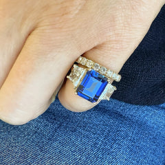 A custom masterpiece, perfect for an alternative bride. This blue corundum center stone is set in yellow gold, and bracketed by two beautifully matched trapezoidal diamond side stones. This modern, iconic engagement ring captured the vision of a creative and imaginative bride