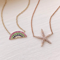 Two necklaces with starfish and rainbow designs on a light background