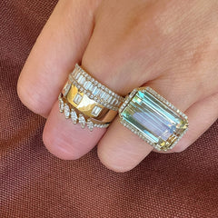 large green tourmaline ring in 14k yellow gold on hand, worn with other rings