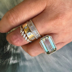 large green tourmaline ring in 14k yellow gold on hand, worn with other rings