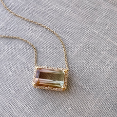 14k yellow gold one of a kind tourmaline necklace with natural diamonds on a book