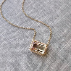 14k yellow gold one of a kind tourmaline necklace with natural diamonds on a book