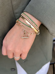 emerlad bracelets worn as part of a stack with gold and diamond bangles and bracelets