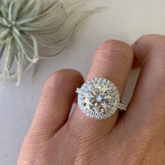 custom made engagement ring with brilliant cut diamond venter, double halo of micropave diamonds and a heavy shank with diamonds worn on a hand