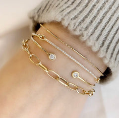 a stack of liven bracelets and bangles in solid 14k yellow gold with diamonds