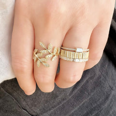 leaf ring on middle finger, ring finger with a stack of textured DNA and baguette bands