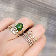 selection of yellow gold rings with a beautiful green ring centerpiece